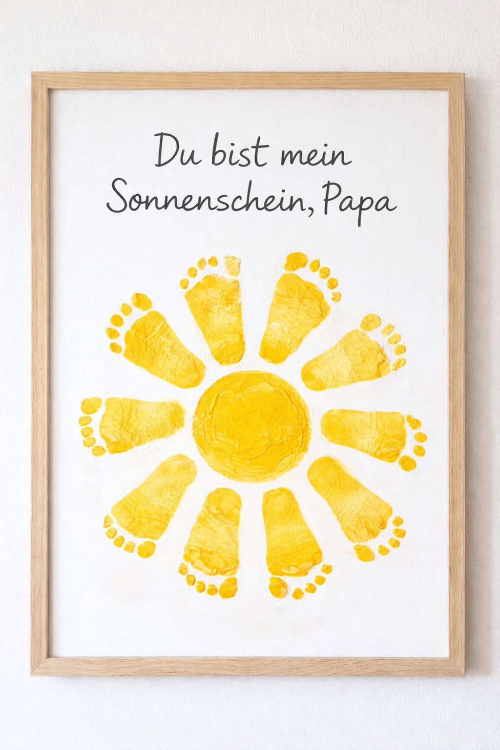 Gerahmtes Bild mit gelber Sonne aus kleinen Fußabdrücken und Spruch „Du bist mein Sonnenschein, Papa“.